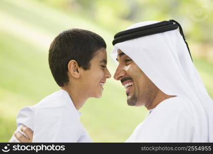 Man and young boy outdoors in park smiling (selective focus)