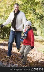 Man and young boy running outdoors in park and smiling