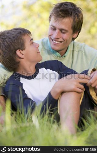 Man and young boy sitting outdoors smiling
