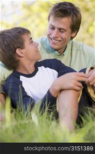Man and young boy sitting outdoors smiling