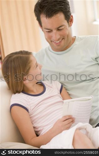 Man and young girl in living room reading book and smiling