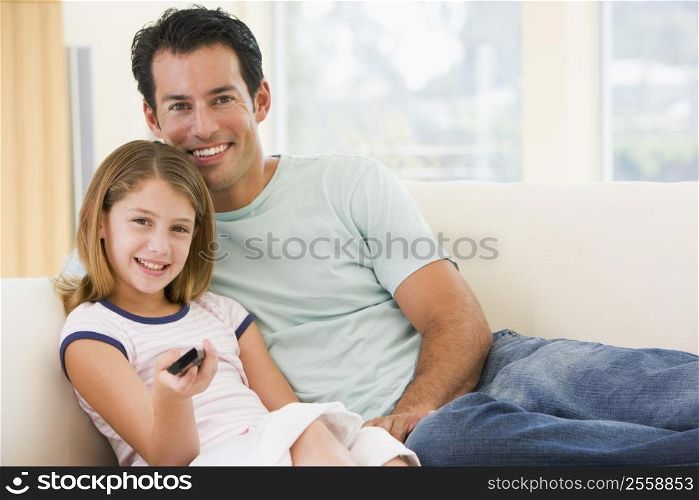 Man and young girl in living room with remote control smiling