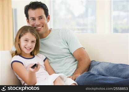 Man and young girl in living room with remote control smiling