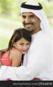 Man and young girl outdoors in park embracing and smiling (selective focus)