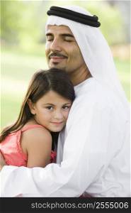 Man and young girl outdoors in park embracing and smiling (selective focus)