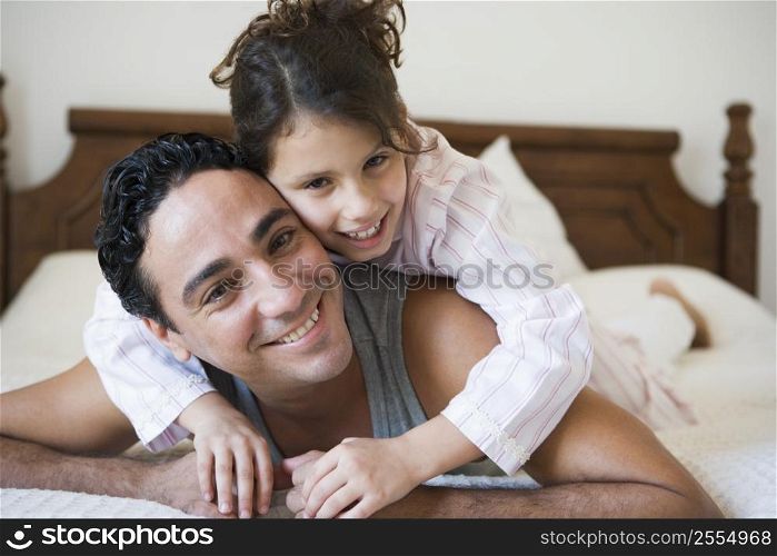 Man and young girl relaxing on bed in bedroom smiling (selective focus)
