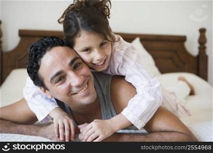 Man and young girl relaxing on bed in bedroom smiling (selective focus)