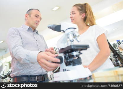 Man and young lady looking at microscope