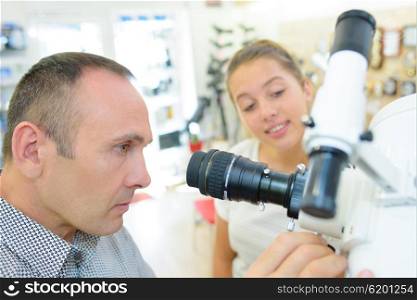 Man and young lady looking at telescope