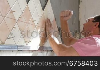 Man applying ceramic tile to a Kitchen wall, Side View, Medium Shot