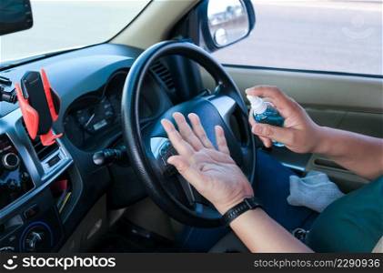 Man applying spray disinfection alcohol product on hand against virus bacteria health prevention inside of his car
