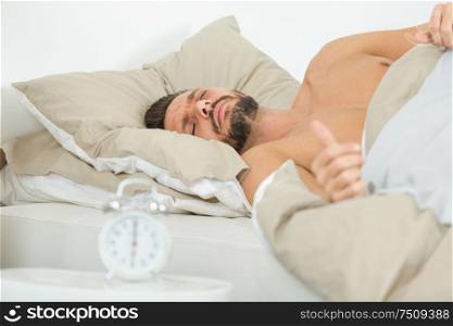 man asleep in bed alarmclock ready six oclock