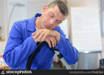 Man asleep leaning on vacuum cleaner hose