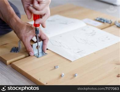 Man assembling furniture at home using screwdriver.. Man assembling furniture at home using screwdriver