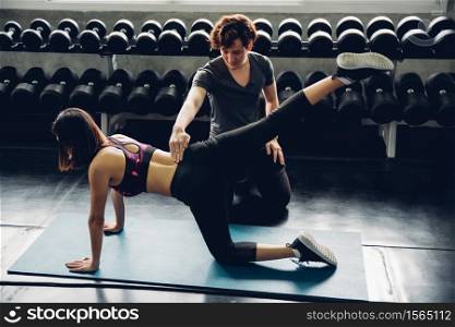 Man Assisting Friend In Exercising At Gym