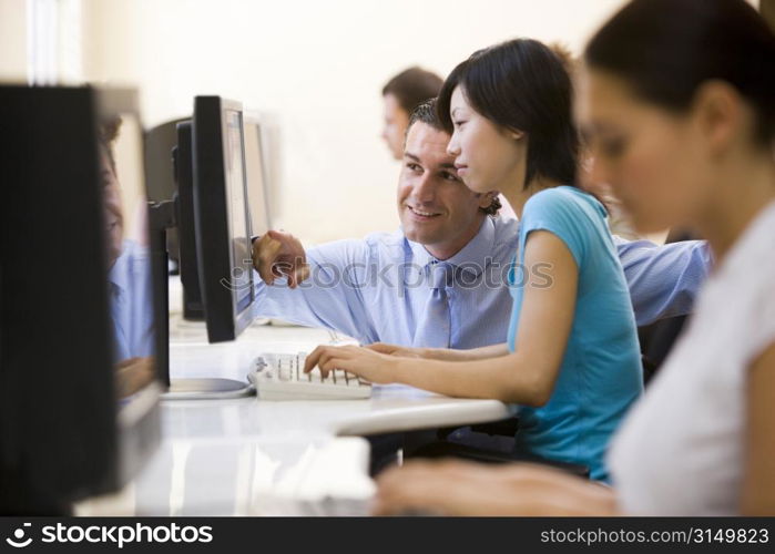 Man assisting woman in computer room smiling