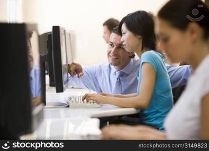 Man assisting woman in computer room smiling