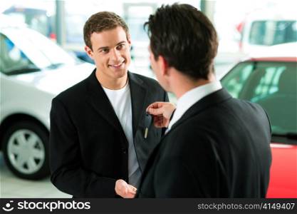 Man at a car dealership buying an auto, the sales rep giving him the key