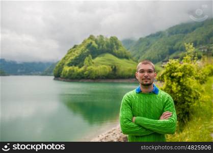 Man at beautiful emerald mountain lake Lungern in Switzerland under low clouds