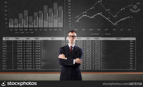 Man at blackboard. Young confident man wearing glasses standing near blackboard