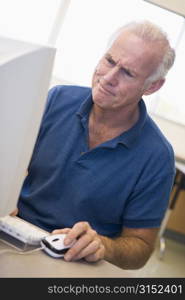 Man at computer looking at monitor confused (high key)