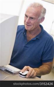 Man at computer smiling and looking at monitor (high key)