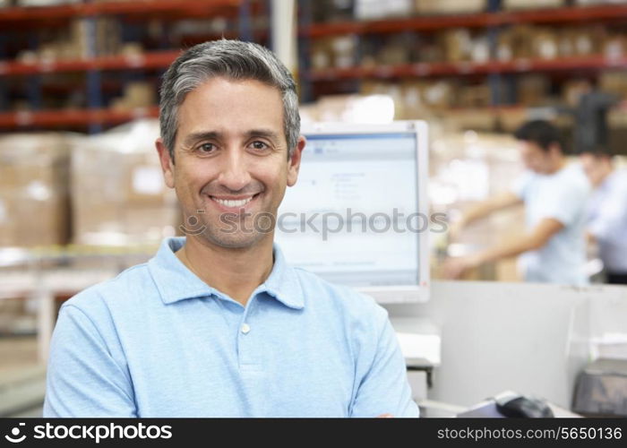 Man At Computer Terminal In Distribution Warehouse