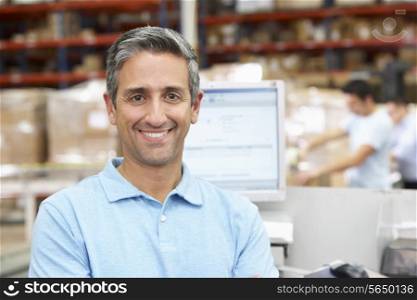 Man At Computer Terminal In Distribution Warehouse