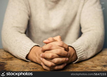 Man at desk with hands folded in prayer