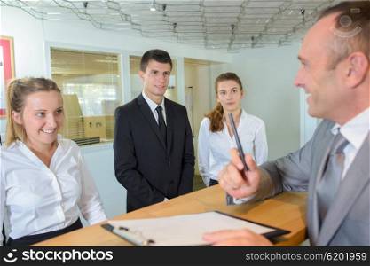 Man at reception of hotel with workers