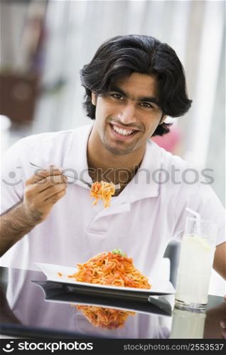 Man at restaurant eating spaghetti and smiling (selective focus)