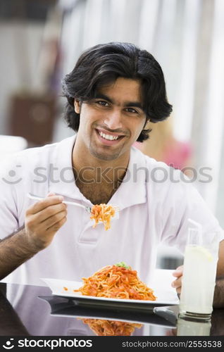 Man at restaurant eating spaghetti and smiling (selective focus)