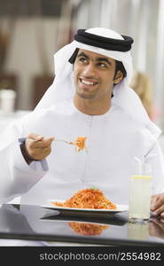 Man at restaurant eating spaghetti and smiling (selective focus)