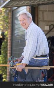 Man at shed sitting on tool bench smiling