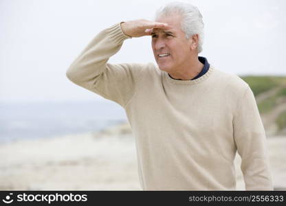 Man at the beach looking out with hand over eyes