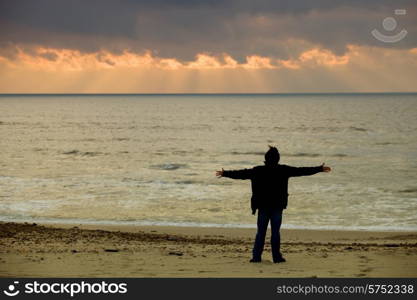 man at the beach sand with arms open