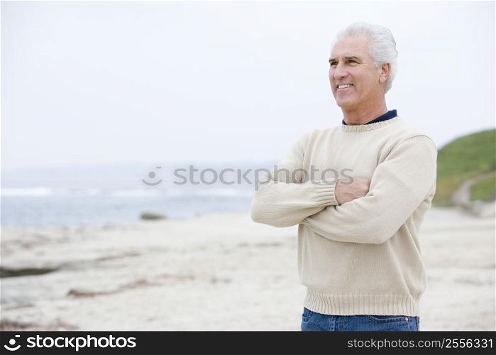 Man at the beach with arms crossed smiling