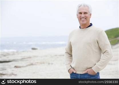 Man at the beach with hands in pockets smiling