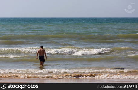 Man at the famous beach of Olhos de Agua in Albufeira. This beach is a part of famous tourist region of Algarve.. Olhos de Agua