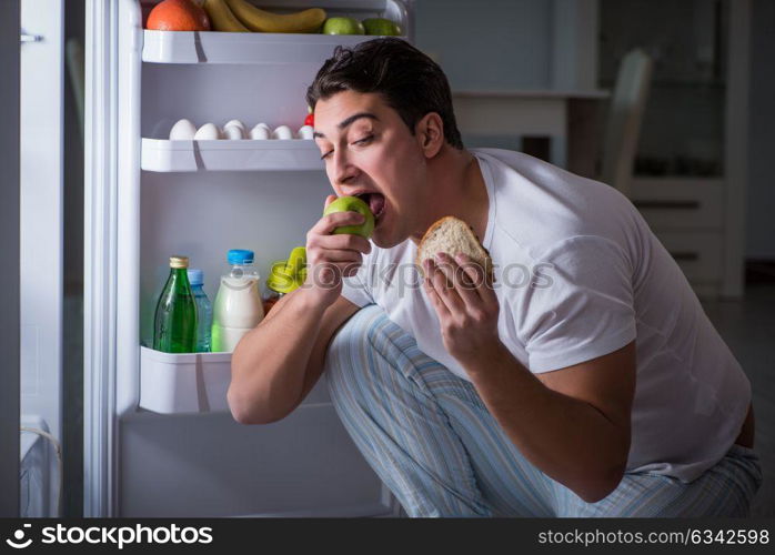 Man at the fridge eating at night