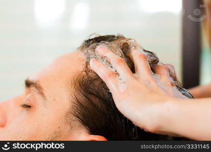 Man at the hairdresser getting his hair washed and rinsed feeling visibly well