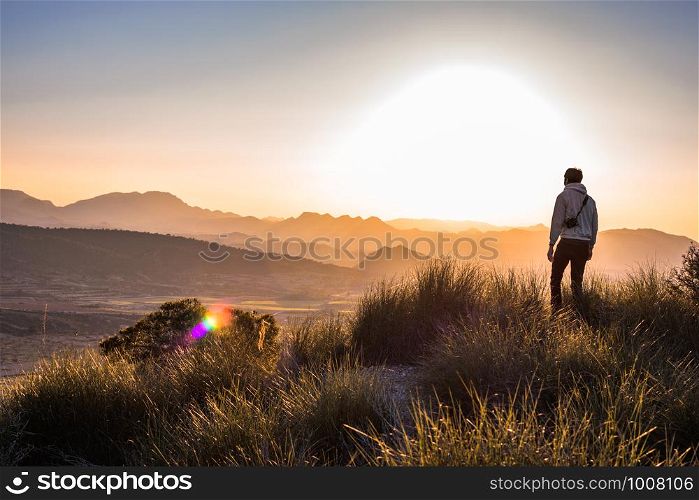 Man at the mountain top against foggy landscape. Outdoor activities. Murcia, Spain, 2019: Young adventurer hiking and taking pictures or photos with reflex camera in countryside. Hobby. Copy space