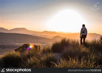 Man at the mountain top against foggy landscape. Outdoor activities. Murcia, Spain, 2019: Young adventurer hiking and taking pictures or photos with reflex camera in countryside. Hobby. Copy space