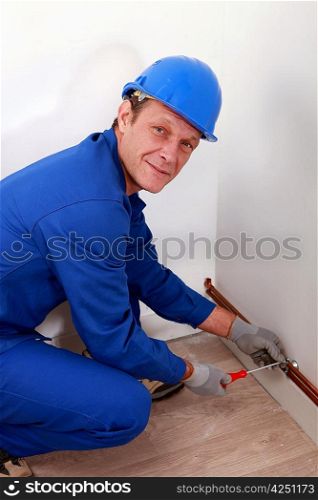 Man attaching copper pipe to wall