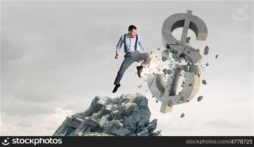 Man attacking dollar symbol. Determined businessman in anger breaking stone dollar sign