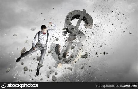 Man attacking dollar symbol. Determined businessman in anger breaking stone dollar sign
