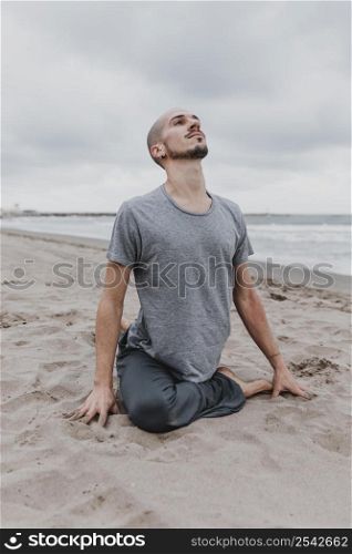 man beach exercising yoga positions