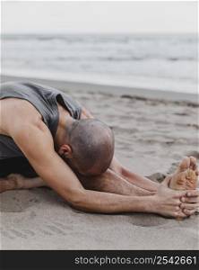 man beach exercising yoga positions sand