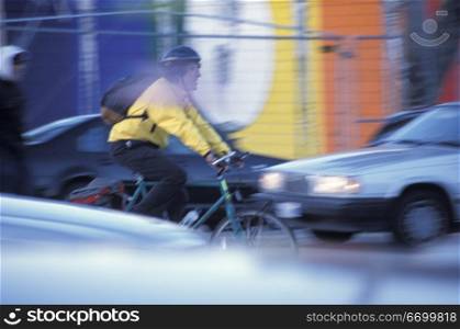 Man Bicycling Through City Traffic