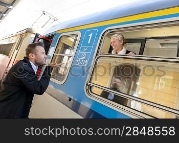 Man blowing kiss to woman on train happy leaving commuter